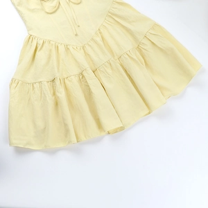 Détail de l'ourlet à volants superposés sur cette robe d'été jaune clair plissée