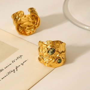Detailed view of hammered gold ring with green gemstone on aesthetic tabletop setting