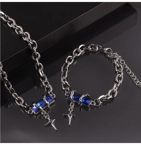 Detail of silver titanium jewelry set with blue zircons and cross pendants on black surface