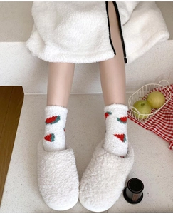 Close-up of fluffy white coral fleece socks with fruit pattern for winter warmth