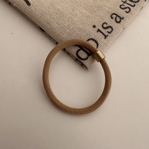 Close-up of high elasticity khaki hair tie with knitted texture and gold metal clasp