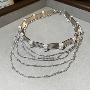 Collier de perles multicouche avec barres en métal argenté et chaînes sur plateau gris
