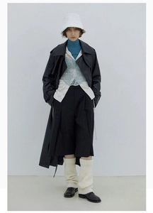 Detailaufnahme von cremeweißen Strick-Beinstulpen mit schwarzer Hose und Lederschuhen