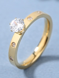 Detail of gold titanium steel ring featuring a claw-set white diamond and small side stones