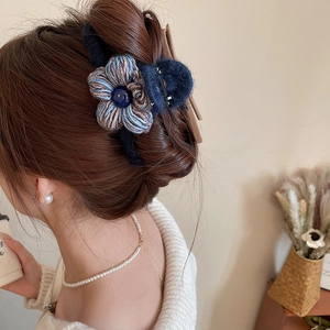 Vue détaillée d'une pince à cheveux avec fleur en crochet bleu foncé sur modèle