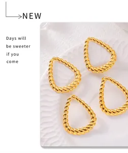 Detail of gold twisted rope earrings with geometric texture on a white ceramic plate