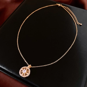 Detailed macro view of a gold-plated circular compass pendant with sparkling crystals
