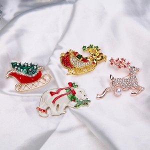 Close-up of four Christmas brooches featuring snowman and reindeer on white silk fabric