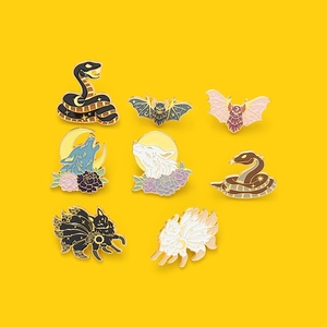 Set of 8 animal enamel pins featuring foxes, wolves, bats, and snakes on yellow background