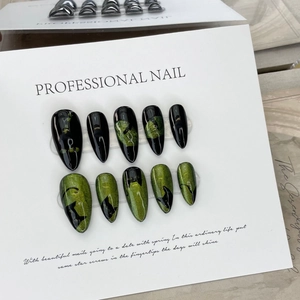 Handmade stiletto press-on nails with black and green cat eye effect on a display card