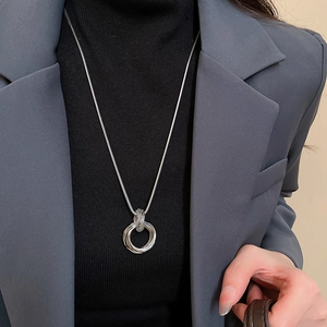 Close-up of layered silver triple-ring pendant with sleek snake chain on female model