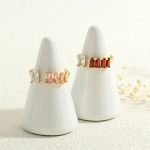 Golden open ring with pink red and clear rectangular zircons on white display