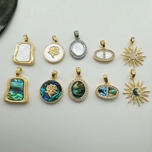 Macro shot of 10 assorted gold and silver DIY pendants with shell inlay and floral designs