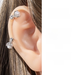 Detailed view of silver octopus-style pearl earrings worn on the cartilage and earlobe