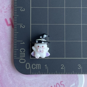 Detailed view of tiny resin ghost with wizard hat on a ruler showing 1.5cm size