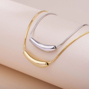 Macro shot of curved cylinder pendant necklace in gold and silver stainless steel