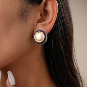 Detail eines runden Vintage-Ohrrings mit goldenem Metallkern und grauer Samttextur