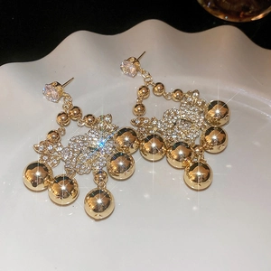 Détail macro de boucles d'oreilles fleurs dorées avec zircons sur une assiette blanche