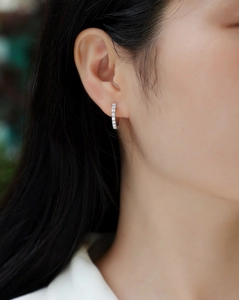 Close-up of minimalist S925 silver hoop earrings with white zircon stones on model ear