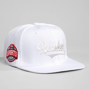 Detailed view of white snapback hat with Reckless 3D embroidery and USA Sports side patch