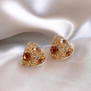 Detailed view of triangular gold stud earrings featuring amber and champagne crystals