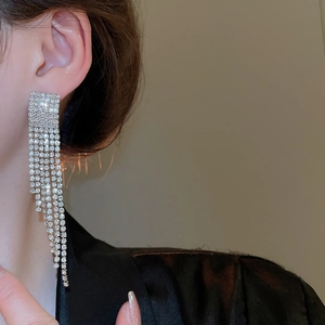 Gros plan de boucles d'oreilles à pompons argentés avec strass brillants sur mannequin