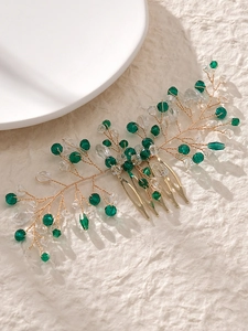 Macro shot of gold bridal hair comb with green crystals and leaf-shaped wire details