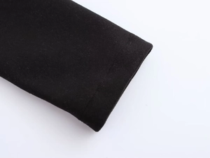 Close-up of black coat cuff stitching and smooth fabric texture on white background