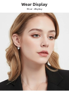 Close-up of minimalist silver hoop earrings worn by a model in a professional black blazer