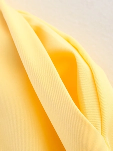 Macro shot of bright yellow safari shirt pocket showing fine twill fabric texture details