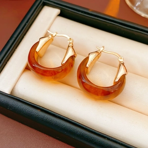 Détail de boucles d'oreilles en résine ambrée en forme de U avec clips en métal doré