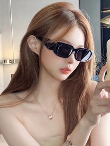 Detail shot of wide-temple geometric sunglasses with gold and silver jewelry on model