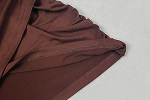 Macro detail of dark brown ruched fabric showing premium stitching and textured knit weave
