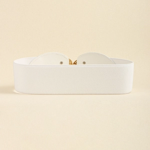 Detail of white elastic waist belt with a golden heart-shaped metal buckle on beige background