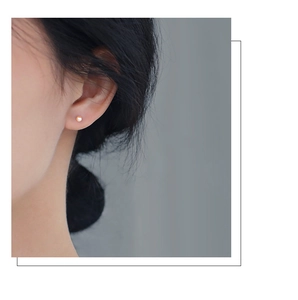 Minimalist small pearl stud earrings worn by a model showcasing a sleek elegant style