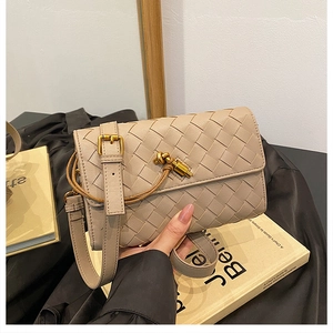Detailed shot of beige woven leather bag with a unique gold knot clasp and flap design