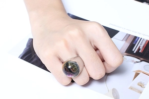 Close-up of woman wearing a silver stainless steel ring with a large purple glitter resin top