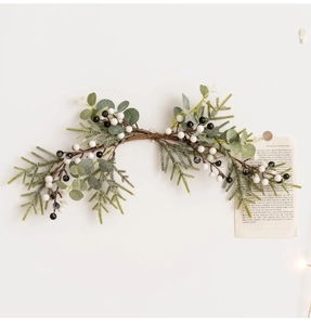 Detail of Christmas wreath with green leaves and berries on a natural vine branch
