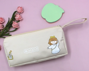Dettaglio dell'astuccio in tela beige con stampa di ragazza cartoon e cinturino a mano