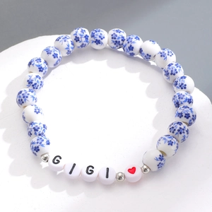 Dettaglio del braccialetto in perline di porcellana con motivi floreali blu e lettere GIGI
