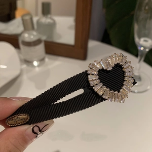 Close-up of heart rhinestone hair clip with black fabric texture and metal charm