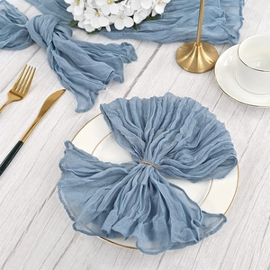 Close-up of blue cheesecloth napkin tied in a bow on a white plate with rustic decor