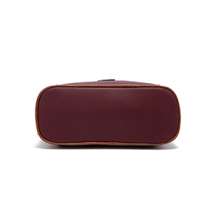 Close-up of deep wine red pebbled leather bag bottom with brown piping and detailed texture