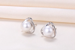 Macro shot of white round freshwater pearl set in a silver hollow triangle frame