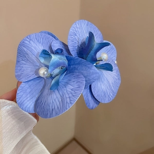Close-up of blue-purple fabric orchid hair clip with gradient petals and pearl detail