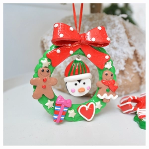 Detailed Christmas wreath ornament featuring a red bow, gingerbread man, and penguin charms