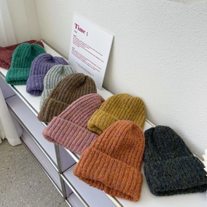 Close-up of thick ribbed knit beanies in various colors on a minimalist display shelf