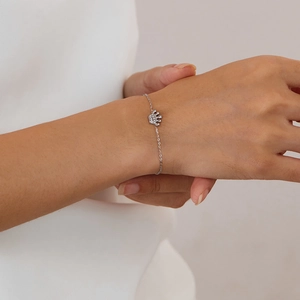 Detailed view of silver stainless steel chain bracelet with crystal crown charm on wrist
