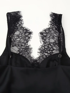 Detail of black satin camisole featuring delicate lace trim and adjustable shoulder straps