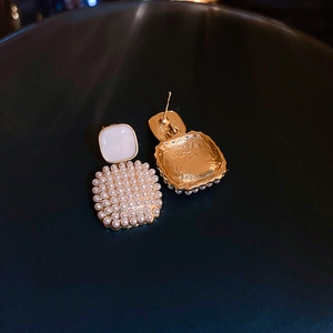 Detailed close-up of square pearl earrings with golden hammered metal texture backing